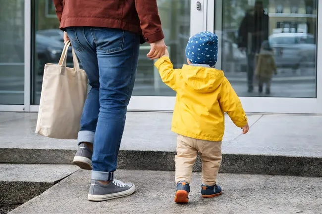 Vater begleitet Kind zum Kindergarten