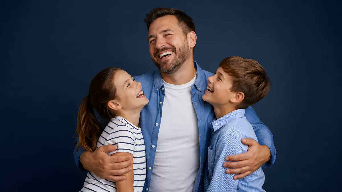 Vater lacht herzlich mit Tochter und Sohn im Arm