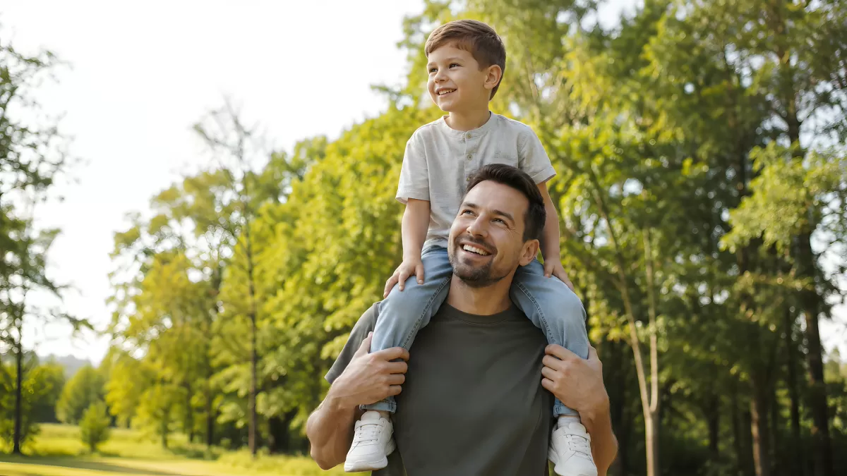 Vater trägt fröhlichen Sohn auf Schultern im Park