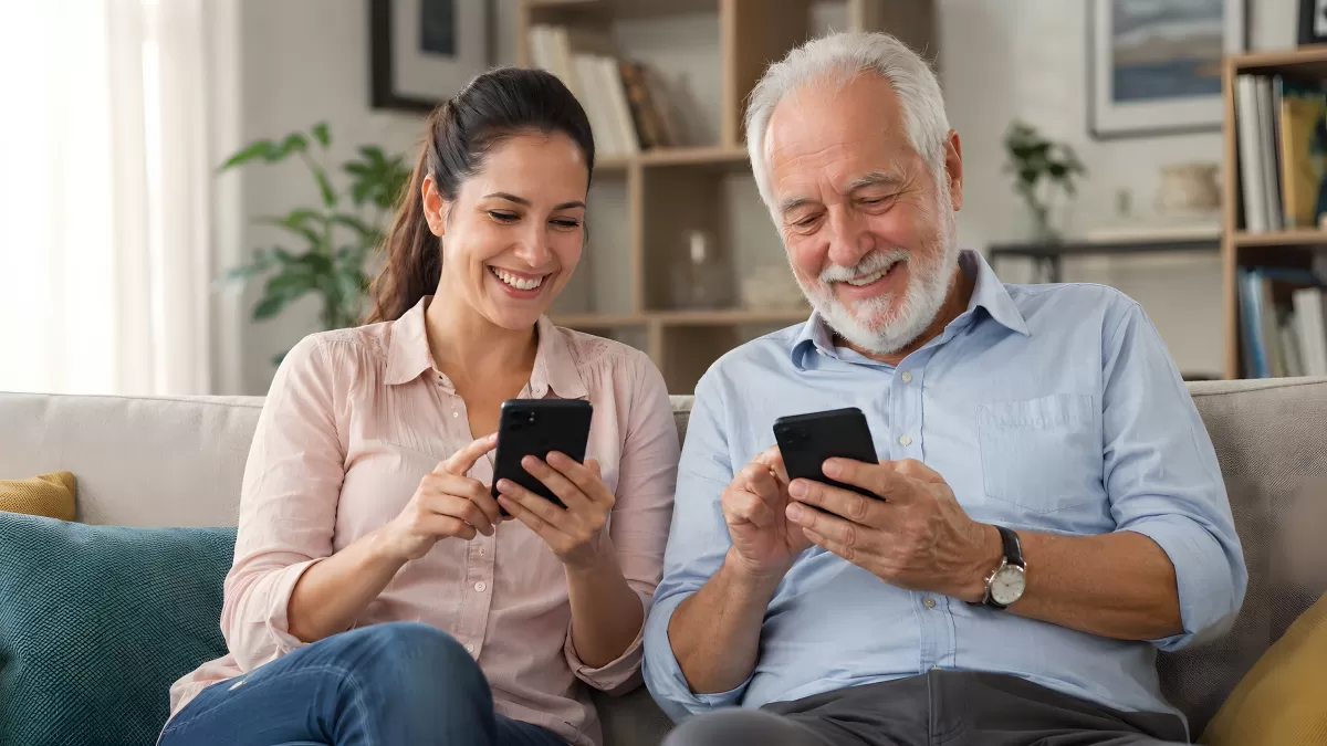 Vater und Tochter lachen gemeinsam mit Smartphones