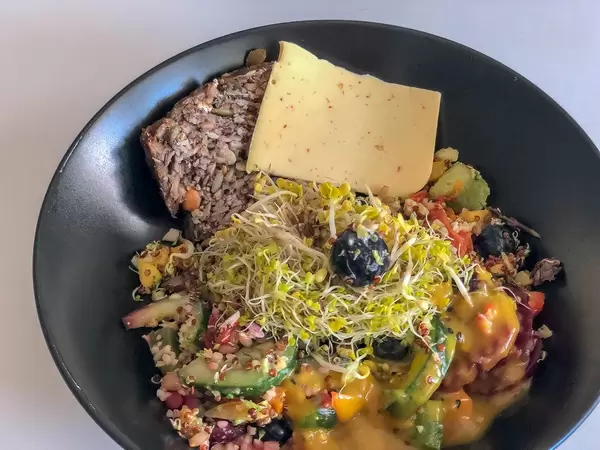 Vegan breakfast with vegetable cheese, sprouts, fruit, vegetables and oat bread without additives
