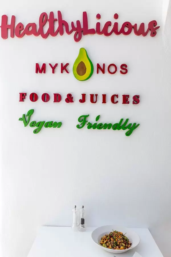 Vegan essen auf Mykonos: HealthyLicious Restaurant. Schild auf weißer Wand, Tisch und Teller