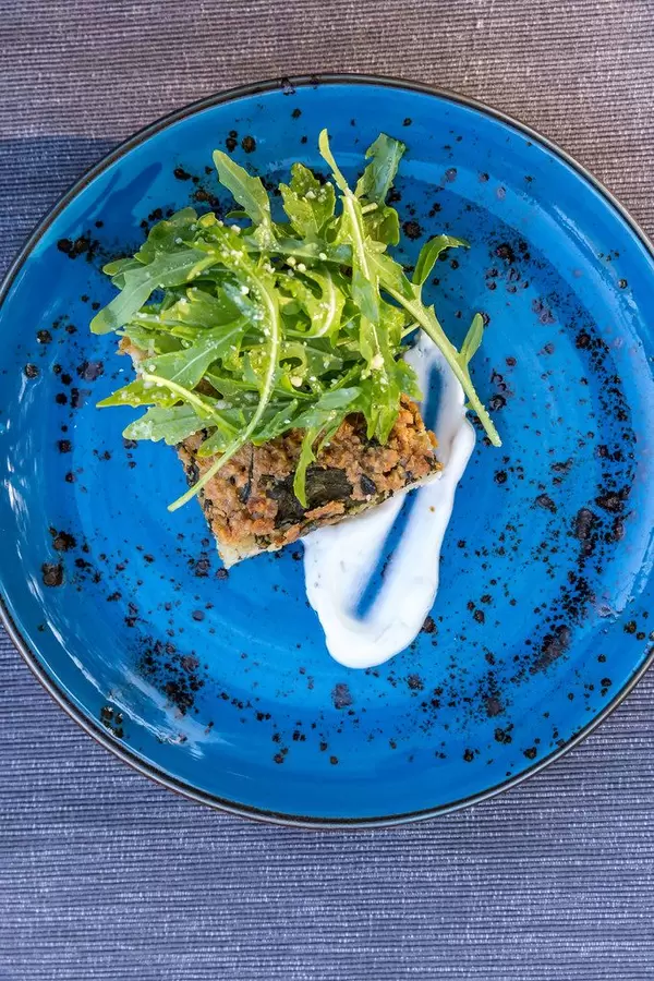 Vegan food in Mallorca. Top view on a blue plate. Summer quiche with rocket salad at Villa vegana