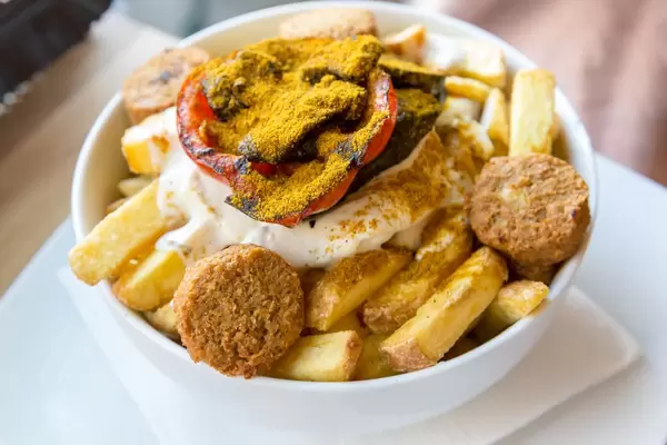Vegan meal at Bunte Burger Cologne: loaded fries with falafel, oriental vegetables, fresh coriander, aioli and mint-yoghurt sauce