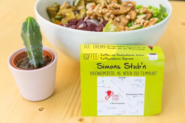 Vegan meal in white bowl with small plant on wooden table in Simons Stub'n restaurant, Munich