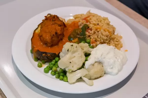 Vegan meal on white plate: Baked aubergine with soy, bulgur and colorful vegetables