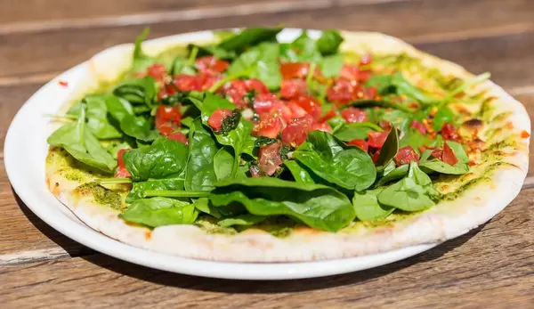 Vegan Pizza with green Pesto, Tomato and Spinach