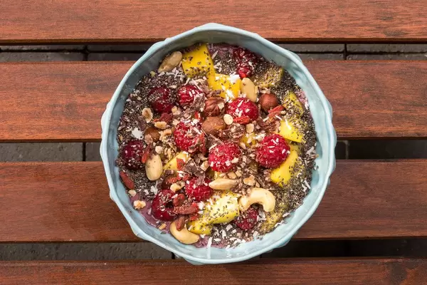 Vegane Acai-Bowl mit Mango, Nüssen, Himbeeren, Gojibeeren, Chia und Schokolade