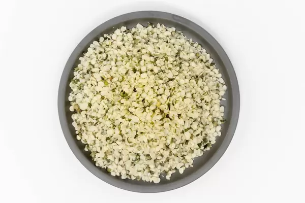 Vegane Bio-Hanfsamen, geschält auf einem schwarzen Teller in der Aufsicht