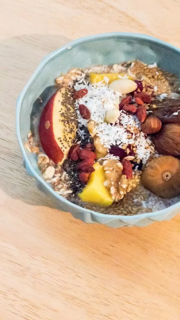 Vegane Bowl mit Feigen, Mango, Apfel, Nüssen und Kokos