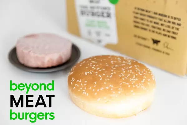 Vegane Burger Patties in der Beyond Meat Burger 10er Box, mit gefrorenem sojafreien und glutenfreien Patty, neben einem Burgerbrötchen