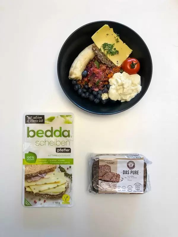Vegane Ernährung mit Hafervollkornbrot ohne Mehl und Hefe, Bedda Scheiben auf pflanzlicher Basis, Beeren, Tomate und Banane. Aufnahme von oben