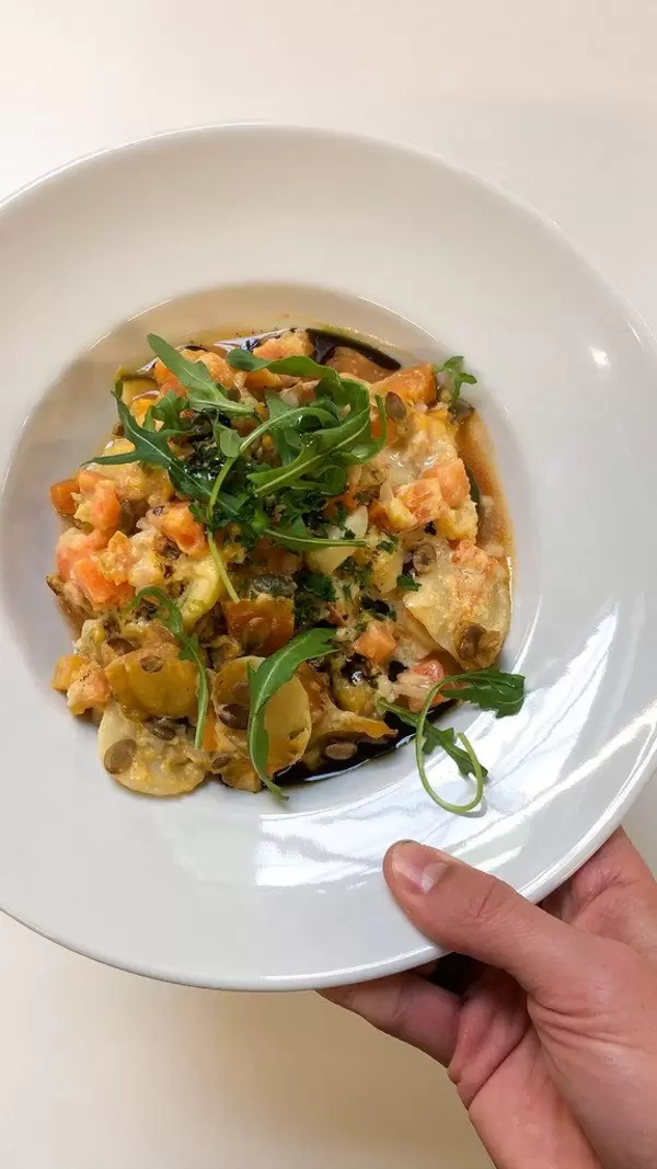 Vegane Gemüsesuppe mit Samen und Rucola in einem weißen Teller, Aufnahme von oben