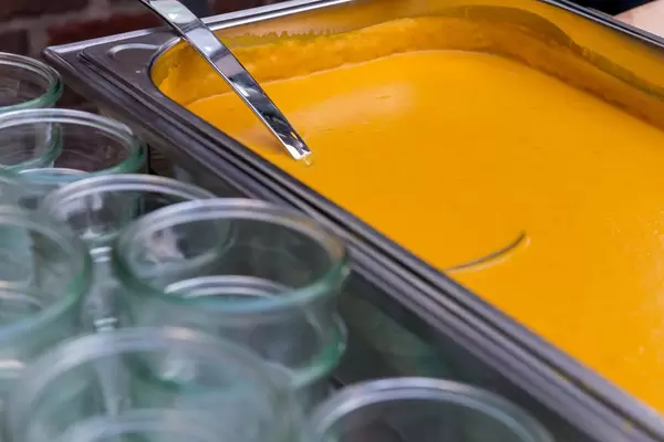 Vegane Kürbis-Kokos-Suppe in einem Warmhaltebehälter bei einem Buffet