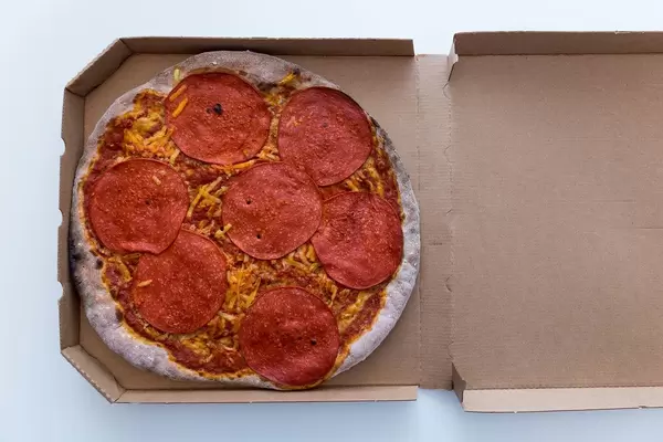 Vegane Pizza mit Salami von Vapiano im Karton zum Mitnehmen. Aufnahme von oben