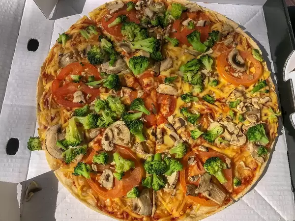 Vegane Pizza von Dominos "Kap Verde" mit Tomaten, veganem Reibeschmelz, Brokkoli und frischen Champignons