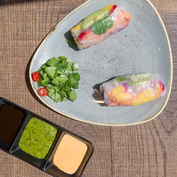 Vegane Rainbow Sommerrollen mit Avocado, Mango, Paprika, Rotkohl, Koriander, Karotten, Eisbergsalat, und Reisnudeln serviert mit drei verschiedenen Saucen