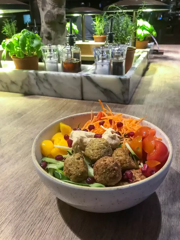 Vegane Rezepte: Bowl mit Falafel, Hummus, Mango, Kirschtomaten, Karotten, Romanasalat, Gurken und Granatapfelkernen