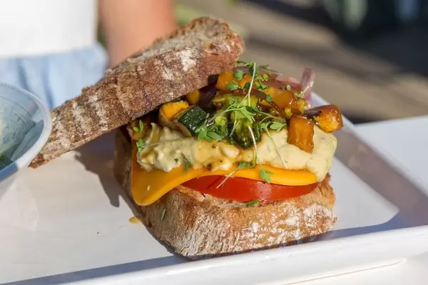 Veganer Burger im Motto am Fluss mit Karotten-Humus, eingelegten roten Zwiebeln, grünem Spargel, Edamame & Mango-Papaya Salat