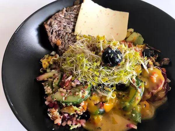 Veganes Frühstück mit pflanzlichem Käse, Sprossen, Obst, Gemüse und Haferbrot ohne Zusatzstoffe