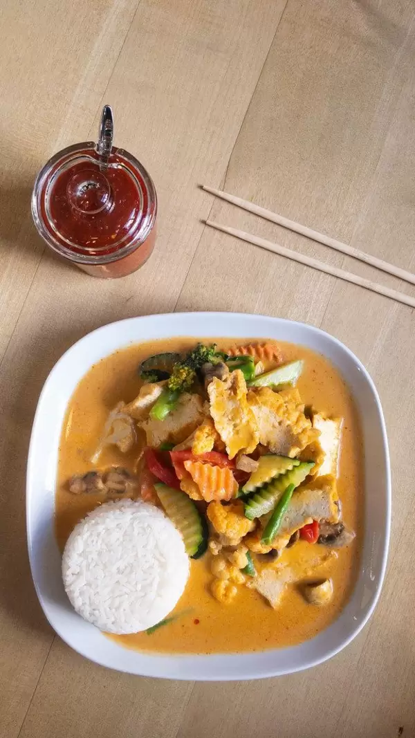 Veganes rotes Thai Curry mit Gemüse, scharfer Soße und Essstäbchen