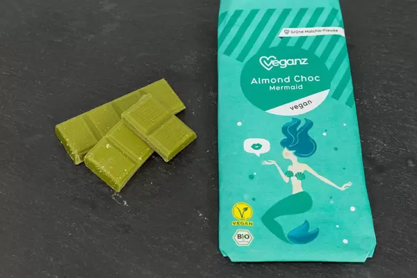 Veganz - Almond Choc mit Matcha - Mandelschokolade mit Verpackung auf schwarzem Hintergrund