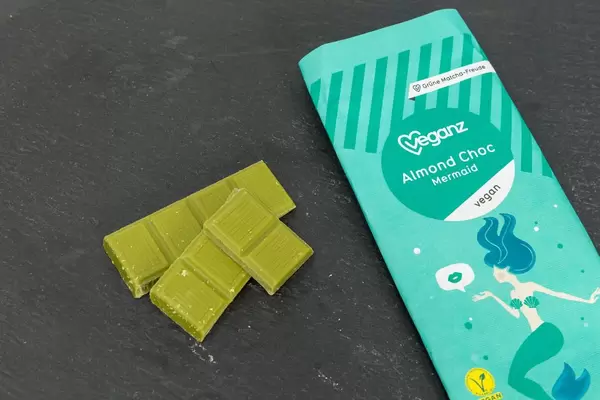 Veganz - vegane Bio-Mandelschokolade mit Matcha Grüntee-Extrakt mit Verpackung auf schwarzem Hintergrund