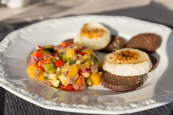 Vegetable dish Ratatui, dark bread "Pumpernickel" with flambéed cheese on a white plate