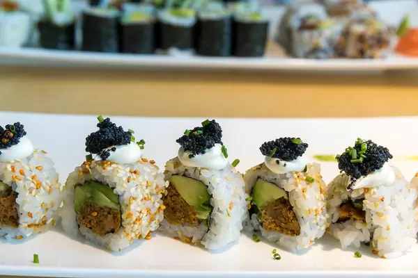 Vegetable main course with vegan sushi, filled with avocado slices, spring onions, spicy sauce, sesame seeds, vegan tuna and vegan caviar