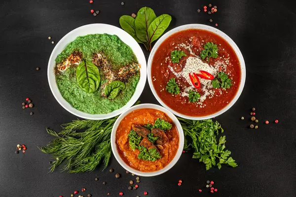 Vegetable puree soup of different colors on a black background, top view
