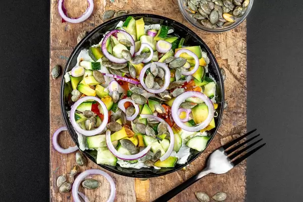 Vegetable salad with pumpkin seeds on an old kitchen board. Top view (Flip 2020)