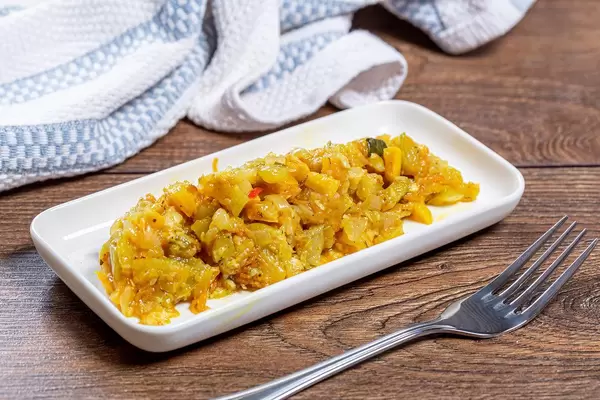 Vegetable stew and fork on brown wooden background