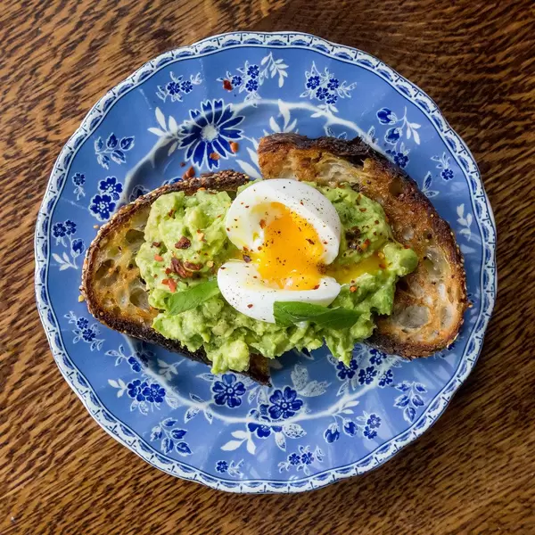 Vegetarian breakfast at The Allis in Chicago: multigrain bread with avocado, egg, chili, basil and lime on a vintage plate, seen from above
