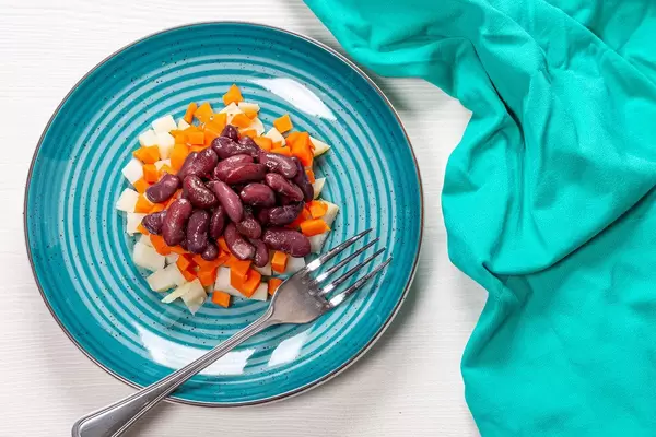 Vegetarian fresh salad of boiled potatoes, carrots and beans with fork on the white table. Top view (Flip 2019)