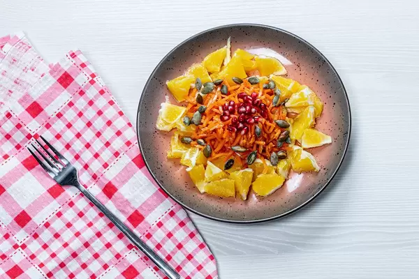 Vegetarian salad with orange, carrot, pomegranate and pumpkin seeds. Top view (Flip 2019)