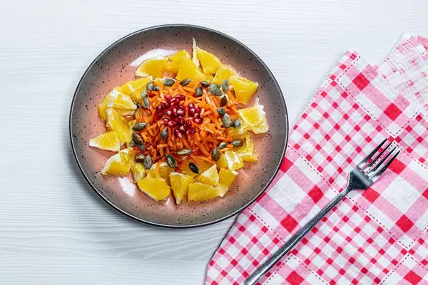 Vegetarian salad with orange, carrot, pomegranate and pumpkin seeds. Top view