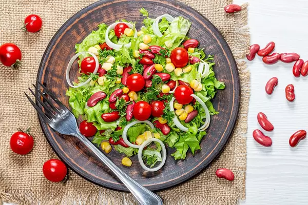 Vegetarian salad with vegetables and red beans in a brown plate on a burlap top View (Flip 2019)