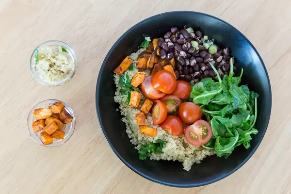 Vegetarische Bowl mit Süßkartoffeln, Cherry-Tomaten, Rukola und roten Bohnen. Draufsicht