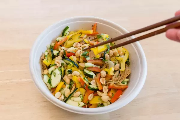 Vegetarische Gemüsepfanne mit Erdnüssen von Lieferservice wird mit Essstäbchen gegessen