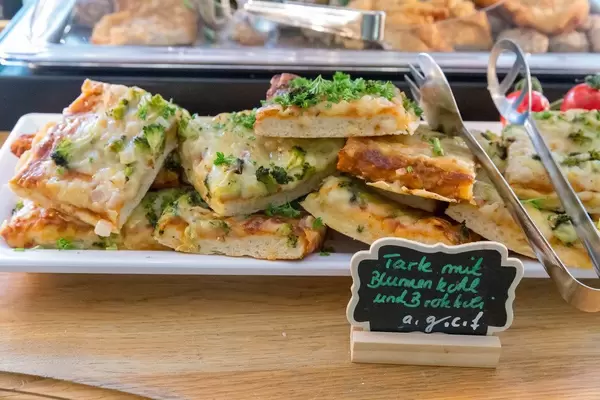 Vegetarische Tarte mit Blumenkohl und Brokkoli auf einer weißen Platte am Essensbüfett