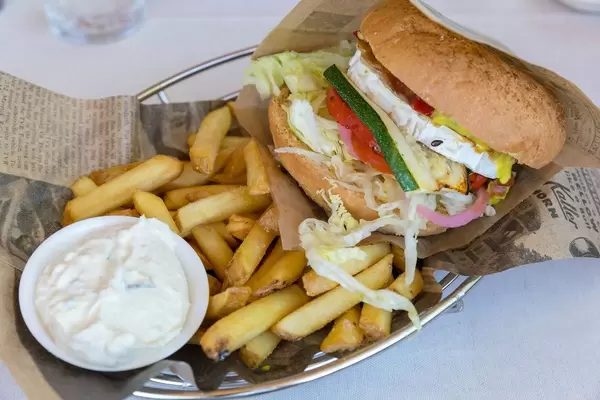 Vegetarischer Gemüseburger im "Bus Burger" Restaurant in Lahti, mit Ziegenkäse, getrockneten Tomaten, Dip, Salat, Senf, Mayo, Gurken & Pommes