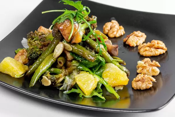 Vegetarischer Saat mit Spargel, Brokkoli, grünen Salatblättern, Orange und Walnüssen