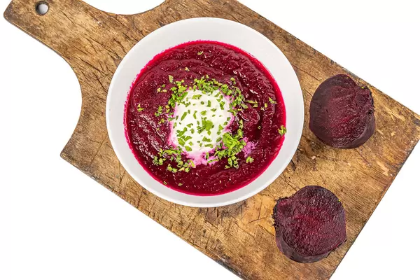 Veggie beetroot soup on old wooden kitchen board, top view