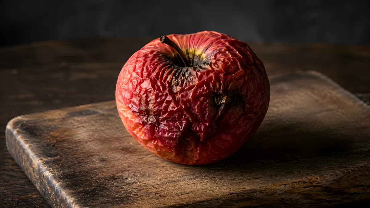 Verfaulter roter Apfel auf altem Holzbrett