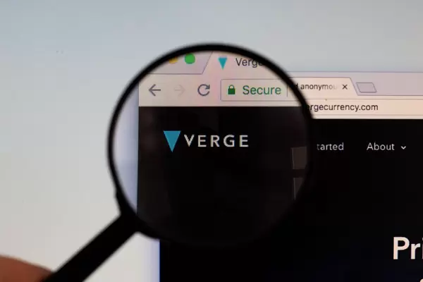 Verge-Logo am PC-Monitor, durch eine Lupe fotografiert