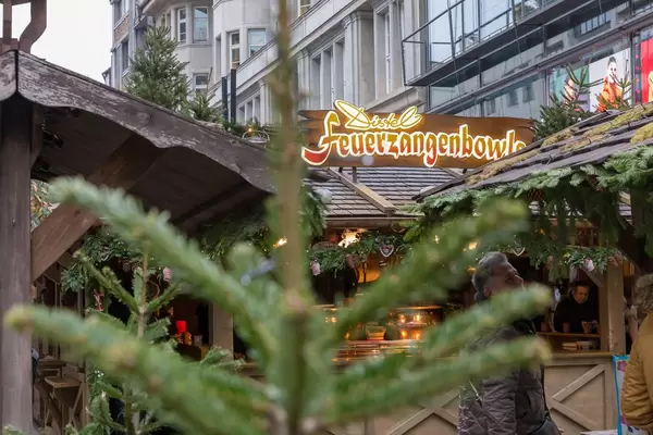 Verkaufsstand von Feuerzangenbowle an Weihnachtsmarkt, im Vordergrund Tannenbaum