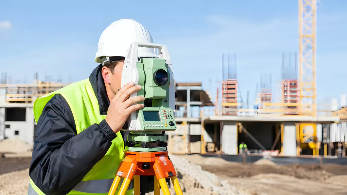 Vermessungstechniker mit Theodolit auf Baustelle