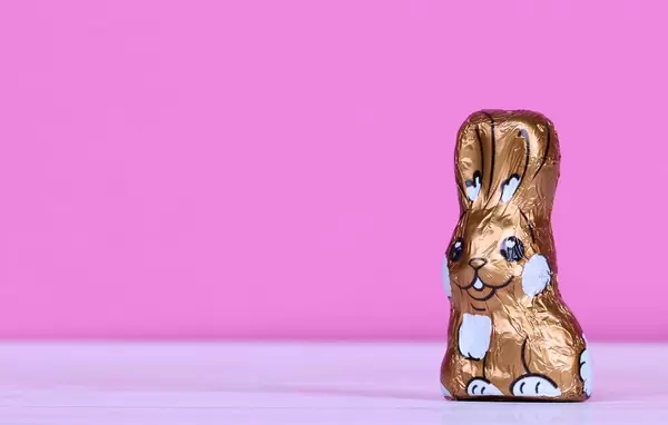 Verpackter Schokoladen-Osterhase mit rosa Hintergrund