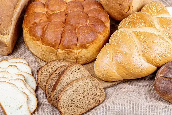 Verschiedene Brotsorten auf einem Holzbrett und auf Sackleinen Nahaufnahme