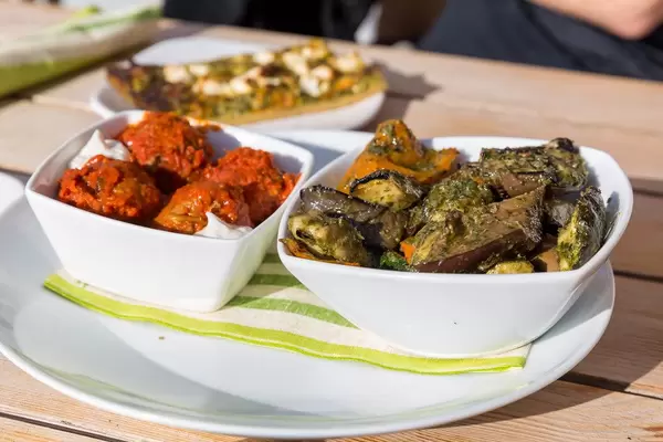 Verschiedene finnische Tapas in weißen Schalen auf einem Holztisch draußen